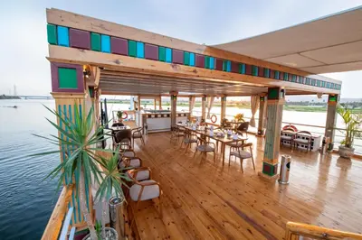 a wooden deck with tables and chairs on the water at Azhar II Dahabiya Luxury Nile Cruise in Luxor
