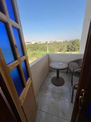 a small balcony with a table and a window at Lokanda lodge&Apartments in Luxor