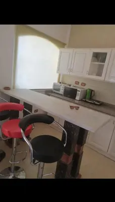 a kitchen with a counter with two stools and a microwave at Luxur sleep in Al Baghdādī