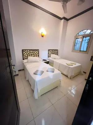 a room with three beds and a window at Anas Nubian Guest House in Aswan