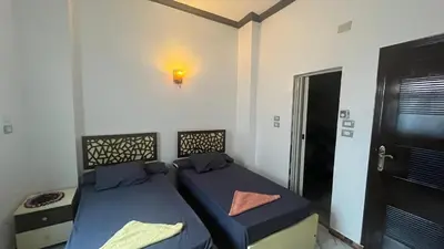 a small bedroom with two beds and a door at Anas Nubian Guest House in Aswan