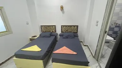 two beds with colorful pillows sitting in a room at Anas Nubian Guest House in Aswan