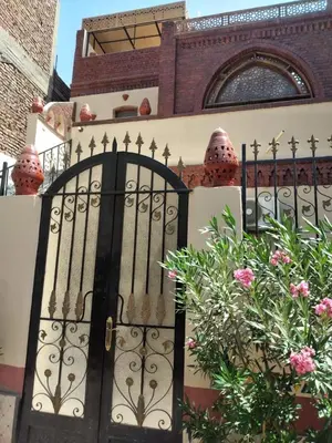 a black gate in front of a building with flowers at Nileview Terrace Dome Apartment in Luxor