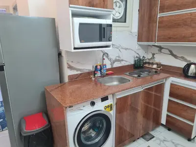 a kitchen with a washing machine and a microwave at Modern Pool View 1BR with Balcony Prime Location on Hurghada Vibrant Promenade in Hurghada