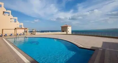 a swimming pool in front of a building with the ocean at كمباوند ذا فيو The View Compound in Hurghada