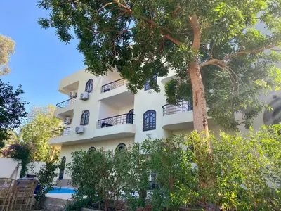 a white building with a tree in front of it at Glenholme Country House in ‘Ezbet Abu Ḥabashi