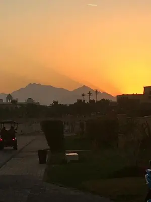 a sunset with a car driving down a street at Stylish & Cozy 50 m2 Studio Chalet in the Sunset Pearl Apartments in Hurghada