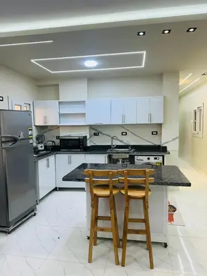 a kitchen with a table and two wooden chairs at شقة بالانتر الغردقة in Hurghada
