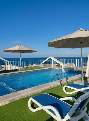a swimming pool with two chairs and an umbrella at Hurghada stylish Apartment on the beach in Hurghada