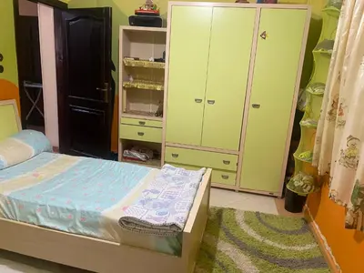 a bedroom with a bed and some green cabinets at فيلا المدينة البعيدة in Naj‘ al Maḩaţţah