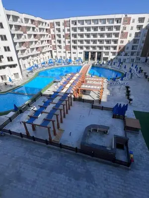 a large building with a swimming pool with lounge chairs at Tiba Golden Beach Hurghada in Hurghada