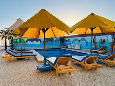 a swimming pool with lounge chairs and umbrellas at Horus Golden Luxor in Luxor