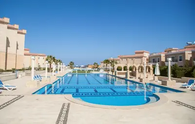 a swimming pool in a resort with lounge chairs at Selena Bay Resort - VIP apartment with Private Beach Area in Hurghada