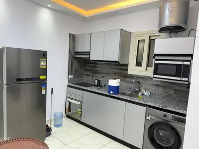 a kitchen with white cabinets and a stainless steel refrigerator at Tartils Beach Resort Al-Ahyaa in Hurghada