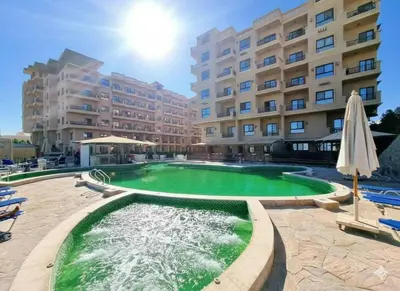 a swimming pool in front of a large building at Tartils Beach Resort Al-Ahyaa in Hurghada