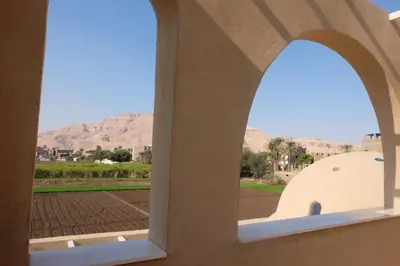 an arched window with a view of a field and mountains at Mountian View Domes in Al Aqālitah