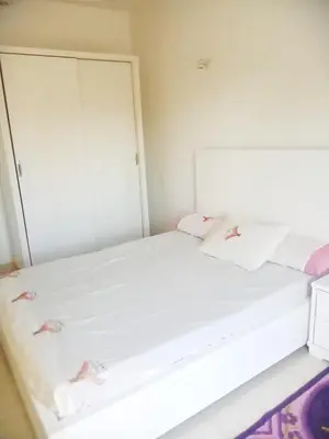 a bed with white sheets and pink pillows in a room at Cozy 2-Bedroom Apartment Ramla, West Bank, Luxor in Luxor