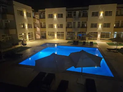 a swimming pool with umbrellas in front of a building at Modern apartment with pool view in Port Ghalib in Port Ghalib