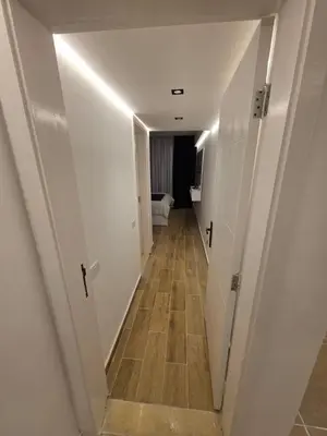 a hallway with white walls and a wooden floor at Cozy Fully Furnished Apartment in Hurghada