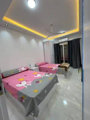two beds in a room with pink and gray sheets at شقه لك ب الكامل فندقي in Safaga