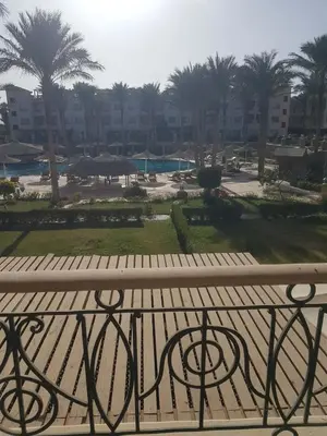 a balcony with a view of a park with palm trees at Sunset Barrel in Hurghada