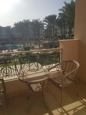 a balcony with a table and chairs and palm trees at Sunset Barrel in Hurghada