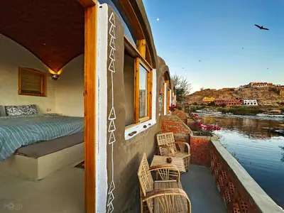 a balcony of a house with a bed and chairs at ASSINGAR Island in Aswan