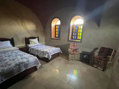 a bedroom with two beds and two windows at Yuhan's Bed & Breakfast in Al Karnak