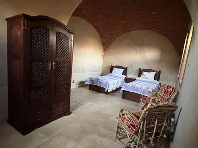 a room with two beds and a cabinet and chairs at Yuhan's Bed & Breakfast in Al Karnak