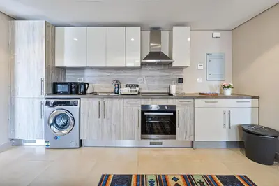 a kitchen with white cabinets and a washer and dryer at Serenity Pool View Holiday Home in Hurghada