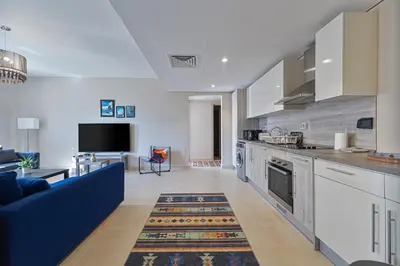 a living room with a blue couch and a kitchen at Serenity Pool View Holiday Home in Hurghada