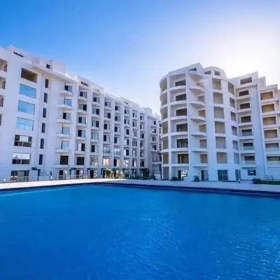 a swimming pool in front of a large apartment building at scandic Beach Hurghada in Hurghada