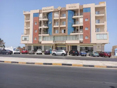 a large building with cars parked in front of it at شقه بمنتجع كذابلانكا in Hurghada