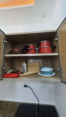 a kitchen cabinet with red dishes and utensils at La Luna Garden Magawish in Hurghada