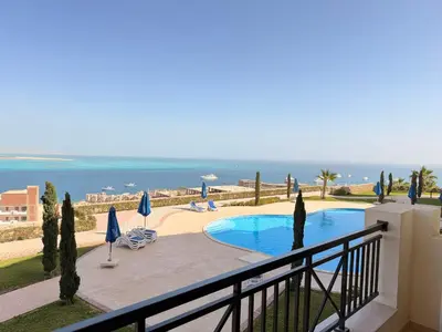 a balcony with a view of a swimming pool and the ocean at Exklusive Ferienwohnung mit traumhafter Meeressicht in Hurghada