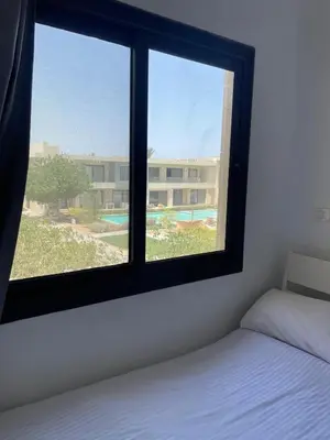 a bedroom with a window with a bed and a building at Two-bedroom apartment in G Cribs in Hurghada