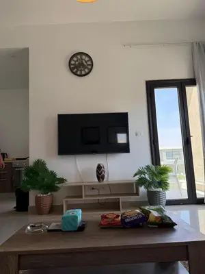a living room with a table and a tv on the wall at Two-bedroom apartment in G Cribs in Hurghada