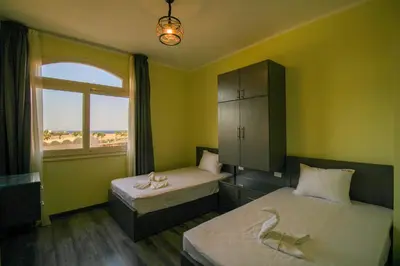 a bedroom with two beds and a window with the beach at All View Apartements, Sahl Hasheesh, El Andalous in Hurghada