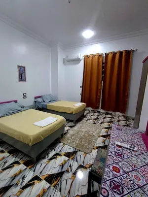 a room with two beds and a rug at El Agamy Hotel Apartment in Luxor