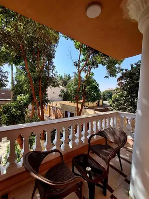 two chairs on a balcony with trees in the background at El Agamy Hotel Apartment in Luxor