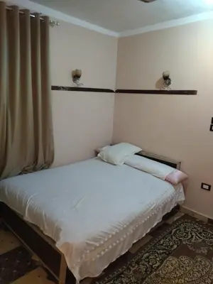 a small bedroom with a bed with white sheets at شقة صغيرة قريبة من شاطئ البحر في سفاجا in Safaga