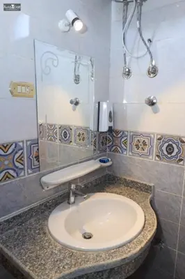 a bathroom with a sink and a mirror at Nefertari Palace apartments in Al Aqālitah