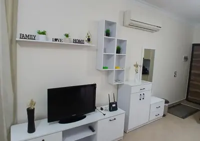 a living room with a tv on a white wall at Modern Apartment in the Britsh Resort in Hurghada