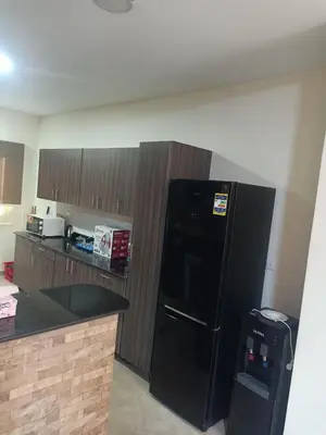 a kitchen with a black refrigerator and wooden cabinets at Sky Star Villa 97 in Hurghada