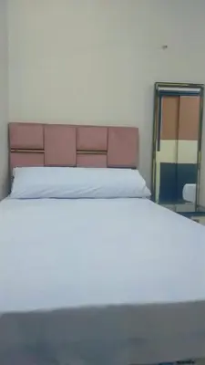 a white bed with a pink headboard and a mirror at happy apartment in Luxor