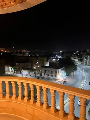 a view of a city at night from a balcony at Luxor Hostel Place in Al Baghdādī