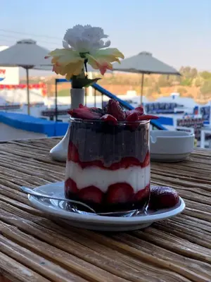 a dessert on a plate on a table with strawberries at Kuliih guest house in Jazīrat Suhayl