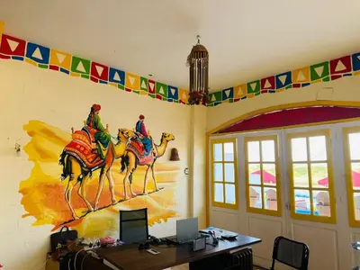 an office with a painting of two men riding camels on a wall at Kuliih guest house in Jazīrat Suhayl
