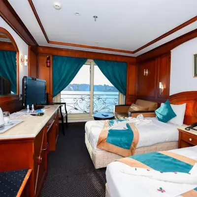 a room with two beds and a desk and a television at فندق نايل ستوري سوهاج in Suwhaj