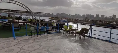 a balcony with tables and chairs on a cruise ship at فندق نايل ايليت سوهاج in Qilfāw